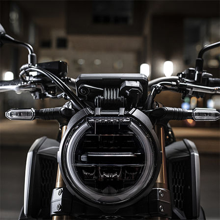 Zbliżenie na przedni reflektor CB650R Neo Sports Café nocą na tle miasta 