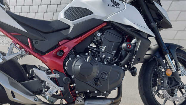 Honda CB750 Hornet z człowiekiem opierającym się o budynek.