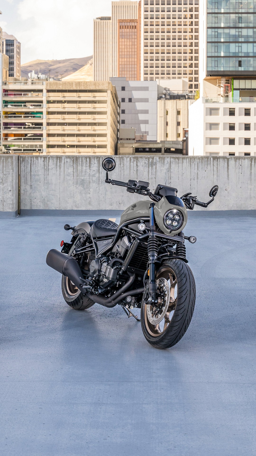 Motocykl CMX1100 na zewnątrz, przed nowoczesnym budynkiem.