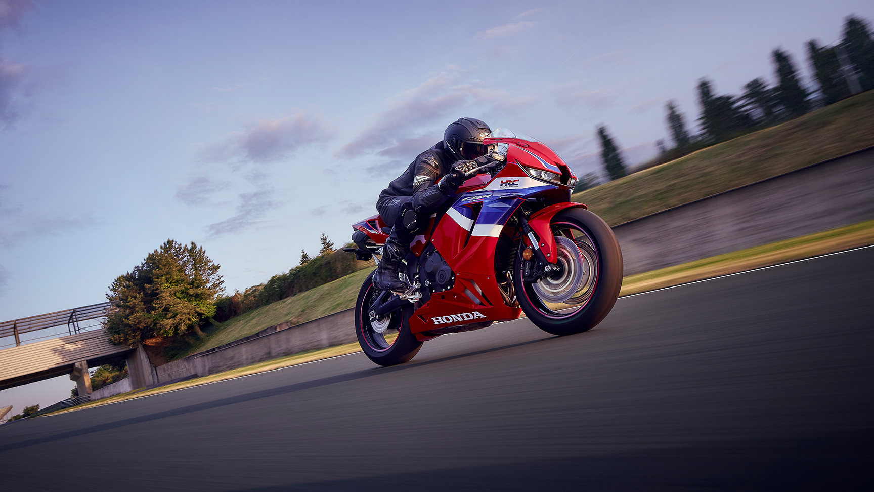 CBR600RR - na torze wyścigowym z kierowcą w zakręcie o zachodzie słońca.